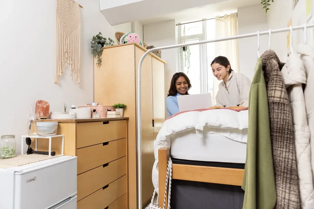 Two students looking at a computer in dorm room.